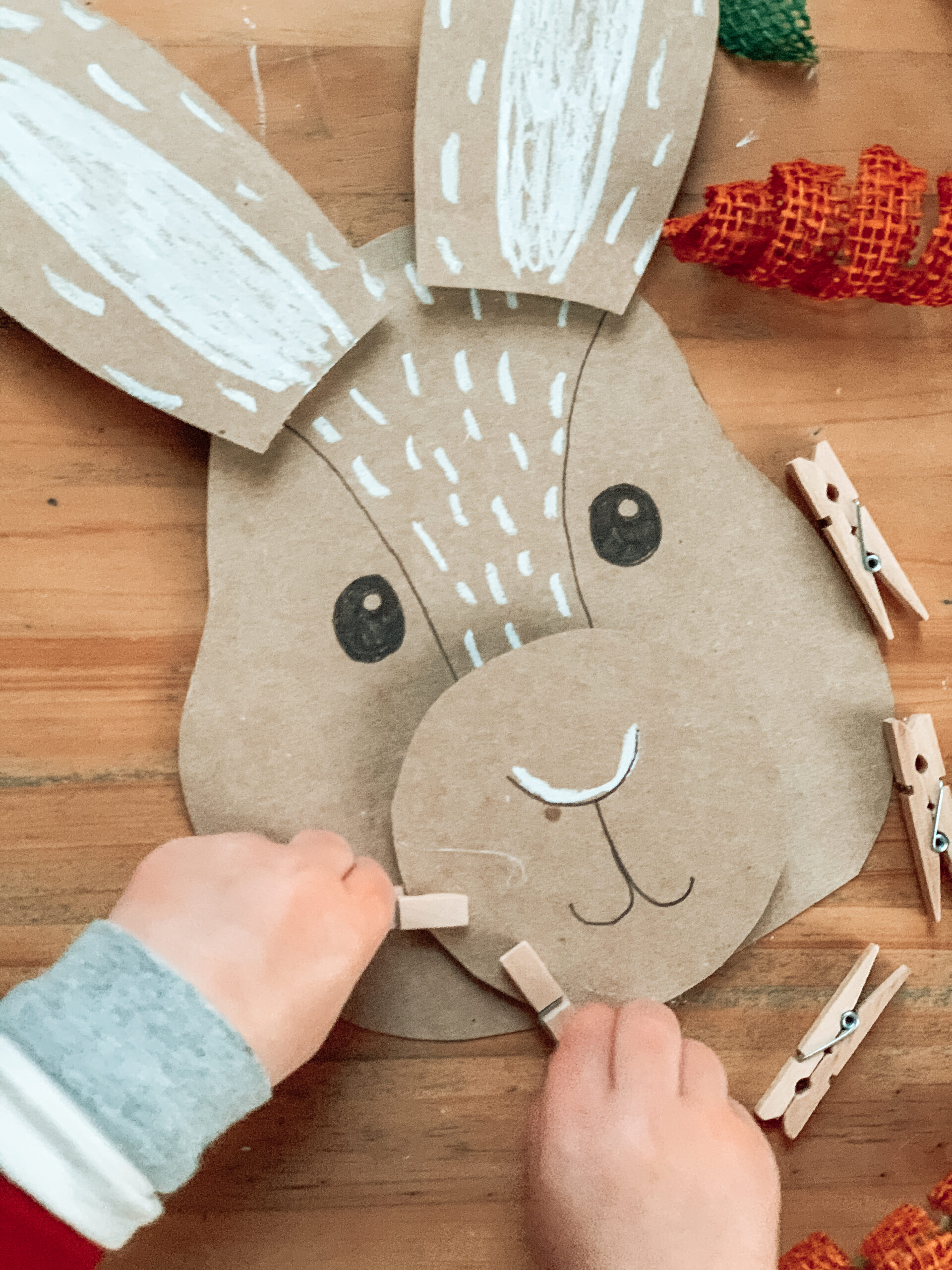 Child playing with Easter bunny craft made of cardboard and clothespins