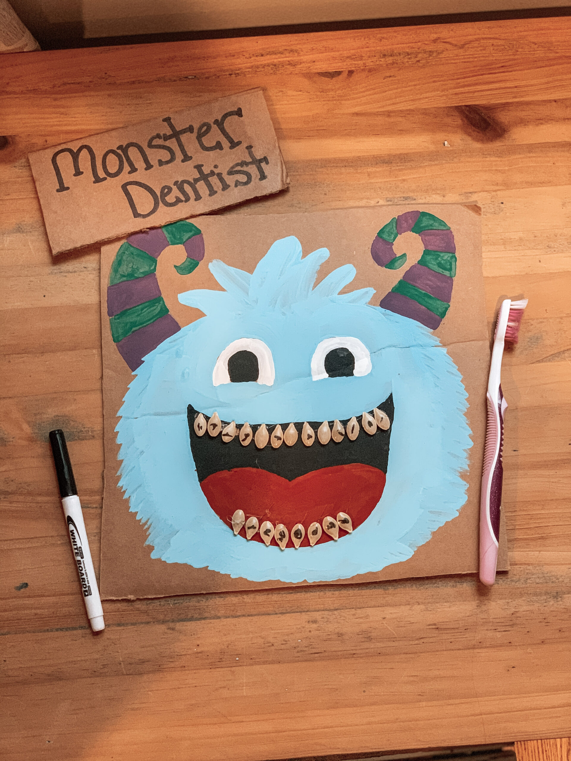 Monster Dentist demonstrating completed repurposed craft for kid's activities with toothbrush and marker pen for kids to play with.