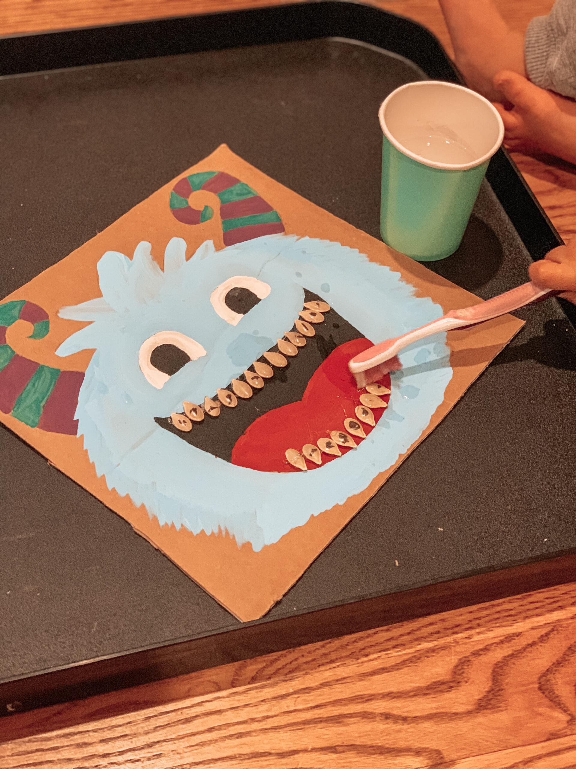 Kid playing with the completed repurposed monster craft. Using a toothbrush on the monster's teeth
