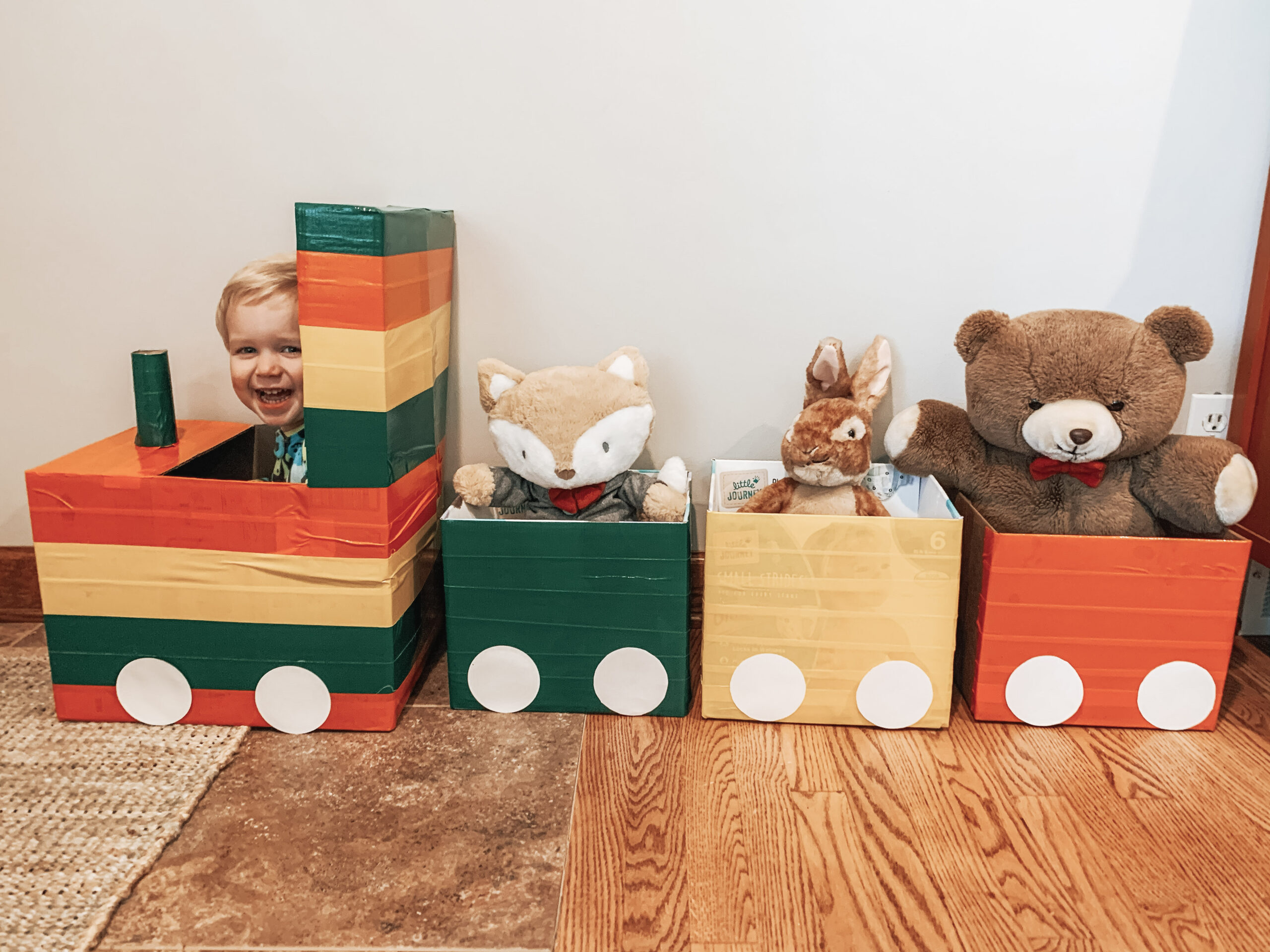 Kid playing with repurposed cardboard train with stuffed animals in the train cars