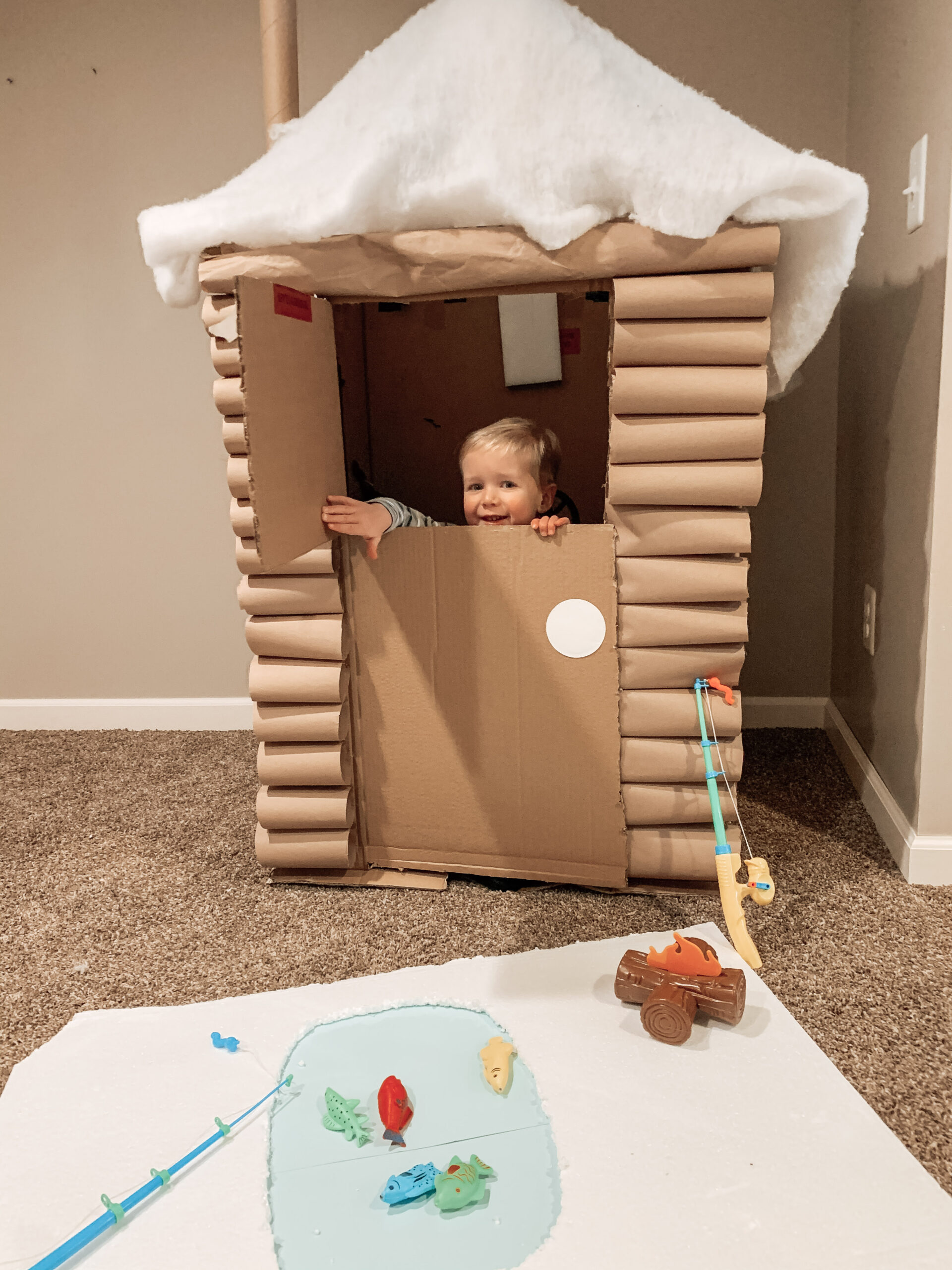 Kid playing with ice fishing cabin craft mad out of repurposed cardboard box for kids activity