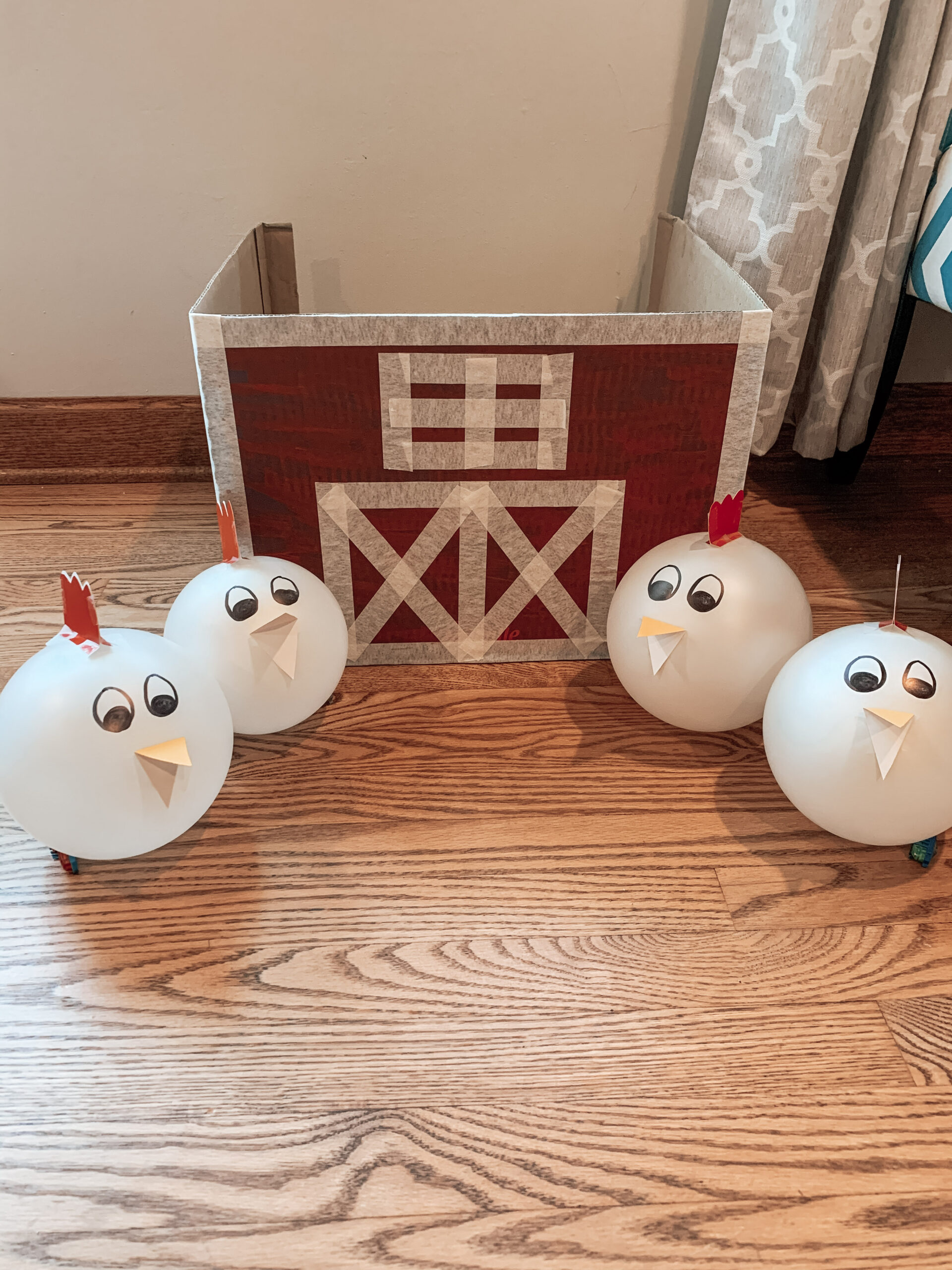 Completed repurposed cardboard kid activity showing the chicken balloons and a cardboard barn