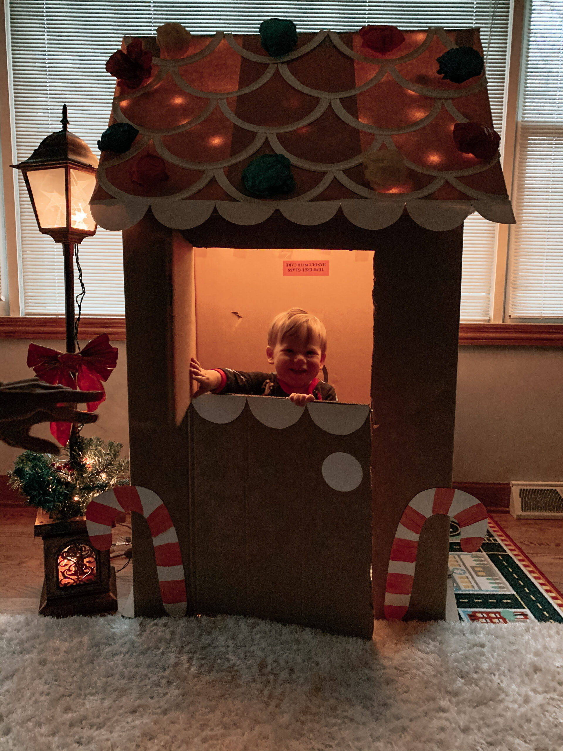 Happy Kid playing with a Christmas gingerbread house. House made with repurposed with cardboard box and a craft activity
