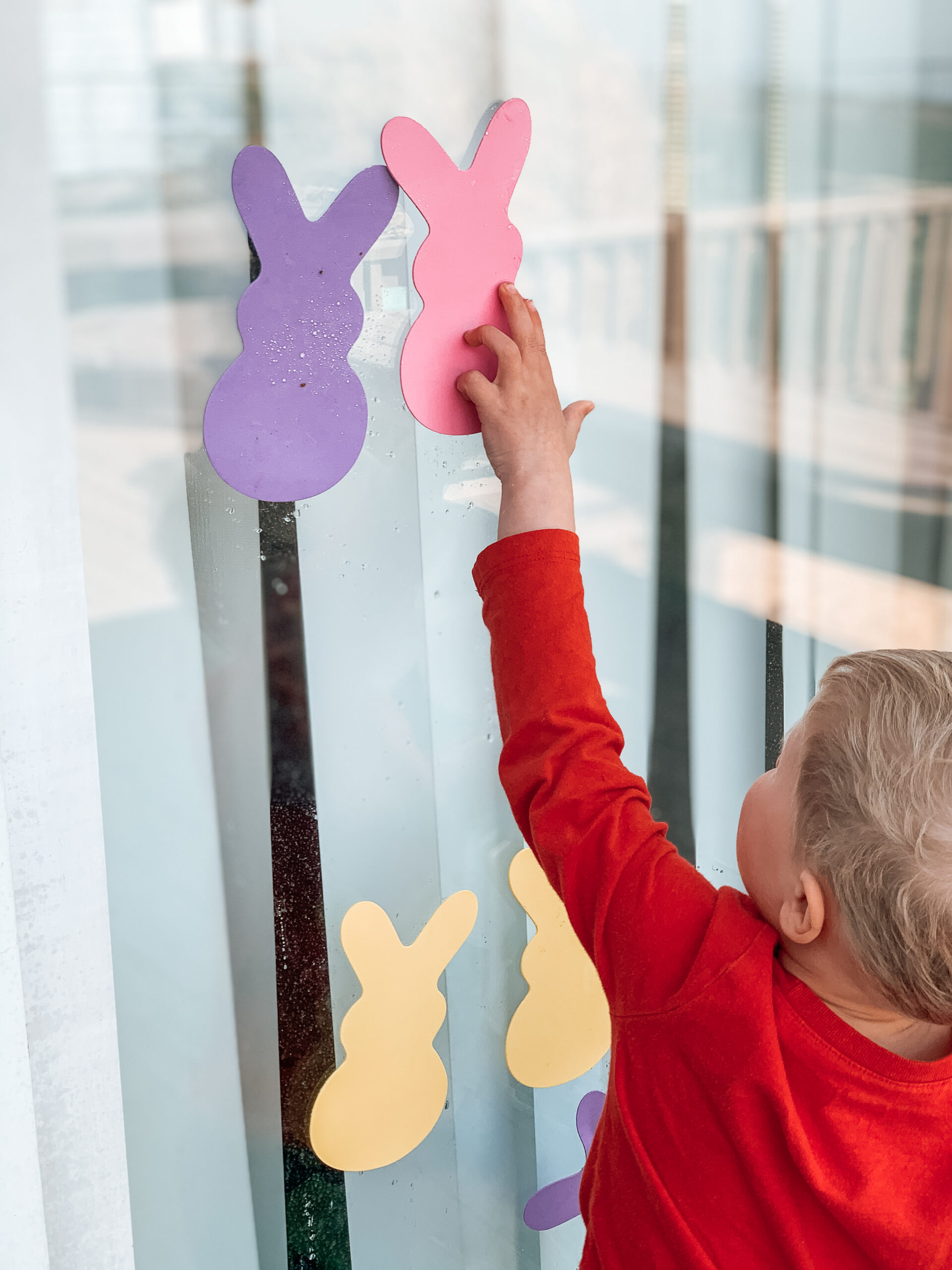 Kids sticking foam bunnies to the window with water from a spray bottle